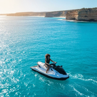 Person riding a jet ski on clear blue water with a vibrant Australian coastline in the background