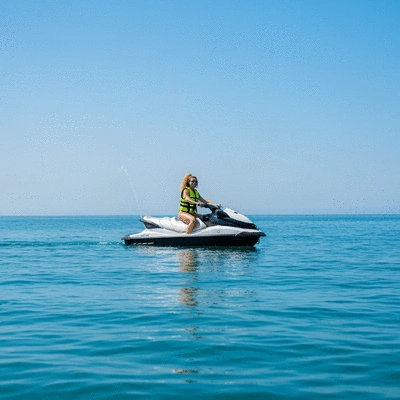 PWC operator wearing a life jacket, confidently riding a jet ski on calm blue water, with a clear sky in the background, no text, no words, no typography, 8K, natural lighting